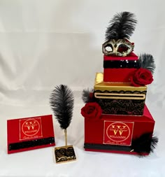 three red boxes with black and gold decorations on them, one has a masquerade