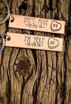 two personalized keychains are sitting on a piece of wood with the words she's mine and i'm her