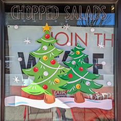 a shop window with two decorated christmas trees