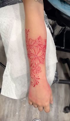 a woman's arm with a red flower tattoo on the left side of her arm