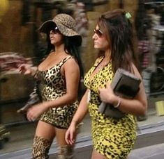 two women walking down the street in animal print dresses and high heeled boots,