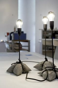 two lamps that are sitting on top of a white table with some rocks in front of them