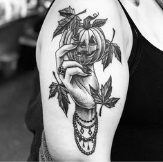 a black and white photo of a woman's arm holding a pumpkin