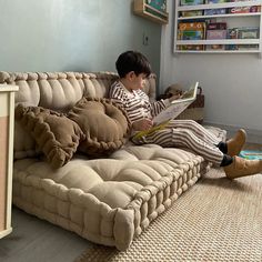 a young boy sitting on top of a couch reading a book