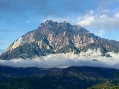 the mountains are covered in clouds and trees