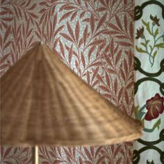 a lamp sitting on top of a wooden table next to a wall covered in flowers