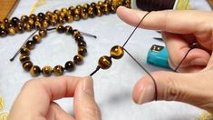 two hands are working on some beads