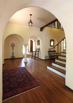 an archway leading to a living room with hardwood floors and white walls, along with a rug on the floor