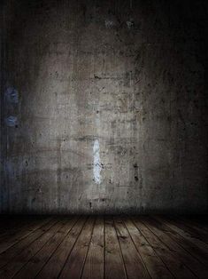 an empty room with a wooden floor and concrete wall in the background is lit by a spotlight