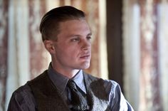 a young man in a vest and tie looking off to the side with his hand on his hip