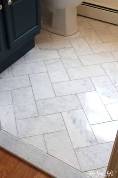 a white toilet sitting next to a blue cabinet in a bathroom on top of a hard wood floor