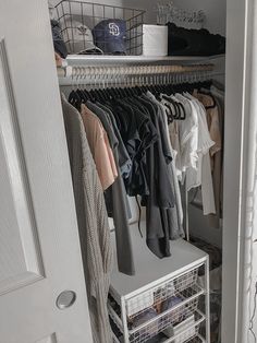 an organized closet with clothes hanging on the rack and other items in bins next to it