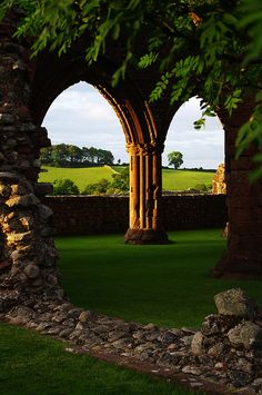 an arch in the grass between two stone pillars