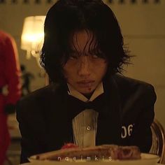 a man in a tuxedo sitting at a table with a plate of food