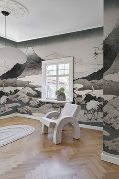 a room with a chair, rug and painting on the wall in front of a window