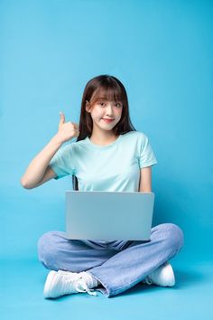 a woman sitting on the floor with a laptop in her lap and giving a thumbs up sign