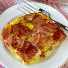 a white plate topped with an omelet covered in bacon next to a fork