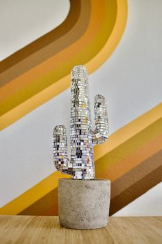 a small cactus sitting on top of a wooden table in front of a colorful wall