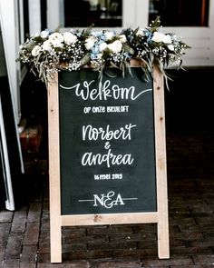 a chalkboard sign with flowers and greenery on it