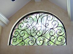 an arched window with wrought iron work on the outside and inside of it in a home