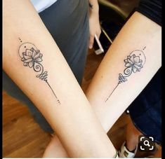 two women with matching tattoos on their legs, both holding hands and one has a flower in the middle