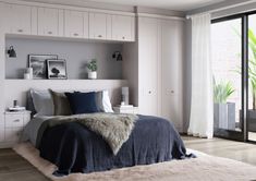 a bedroom with white and grey walls, wooden flooring and a large bed in the middle