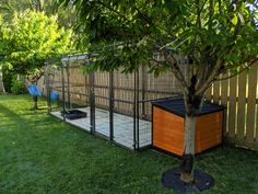 a fenced in area with a tree and small dog house