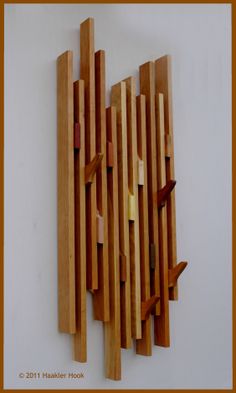 a wooden sculpture on the wall with many pieces of wood sticking out of it's sides