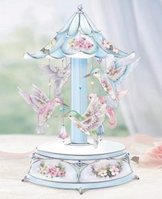 a blue carousel with pink flowers and birds on it