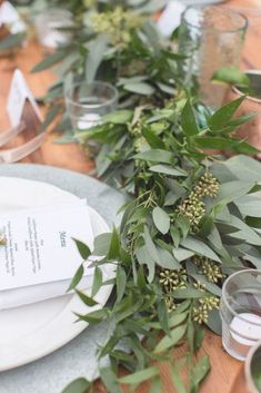 the table is set with greenery and place settings