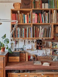 an old wooden desk topped with lots of books next to a book shelf filled with books