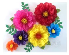 colorful paper flowers are arranged on a white surface