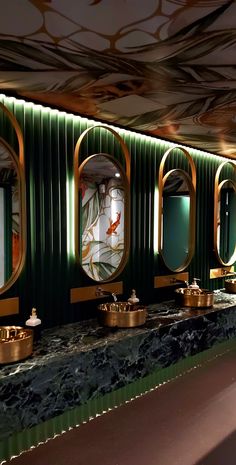 an art deco bathroom with green walls and gold trim on the mirror, sinks and mirrors