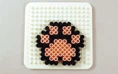 a white square with black and orange beads on it