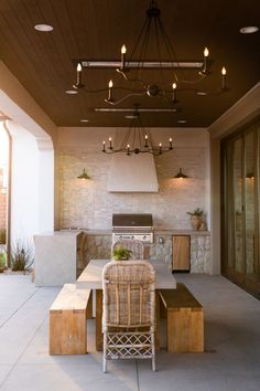 an outdoor kitchen and dining area is shown in this image, with lights on the ceiling