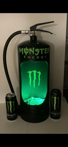 the monster energy drinker is lit up with neon green lights and two cans next to it