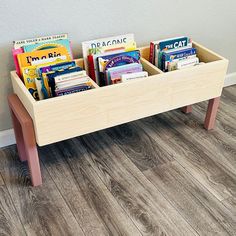 a wooden toy bench with books in it on the floor next to a white wall