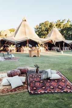 tents set up in the grass with pillows and rugs