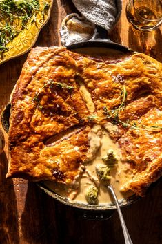 a pot pie with broccoli and cheese in it on top of a wooden table