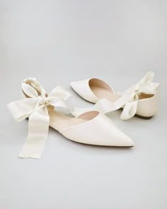 two pairs of white shoes with bows on them