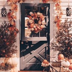 a front door decorated with pumpkins and flowers