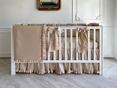 a white crib with pink ruffled bedding and a mirror above the crib