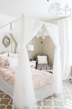 a white canopy bed sitting in a bedroom next to a window with curtains on it