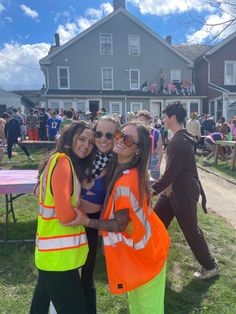 two girls hugging each other in front of a house with people on the lawn behind them