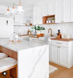 a kitchen with white cabinets and marble counter tops, along with wooden stools in front of the island