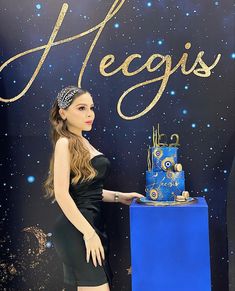 a woman standing in front of a blue cake on top of a table next to a sign that says heggis