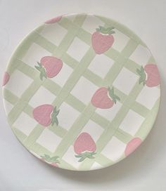 a plate with strawberries on it sitting on a white tableclothed surface in the shape of a checkerboard pattern