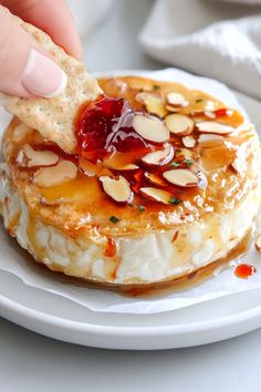 a person dipping some kind of food on top of a white plate with crackers