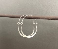 These simple earrings are made from sterling silver wire, that's been shaped into a U shape and hammered smooth and flat. It's linked to a thinner U shape wire on top to create an oval shape hoop. They are tumble polished which strengthens the metal and gives it a high shine.  Total length of hoops are 1 3/8" and measure about 1" wide. Made to order. Production time varies depending on order volume. Oval Hoop Earrings, Out Of Shape, Earrings Minimalist, Recycled Metal, Simple Earrings, Jewelry Earrings Hoops, Saint Louis, Ear Wire, Silver Wire