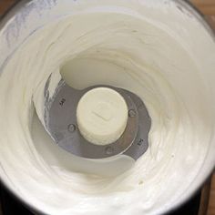 a blender filled with white liquid on top of a wooden table